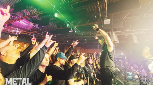 Unearth performing a high-energy live metalcore show, with band members playing guitar, bass, and drums on stage under concert lighting.