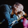 Chester Bennington of Linkin Park performing live on stage with microphone, delivering an intense rock performance under dramatic lighting