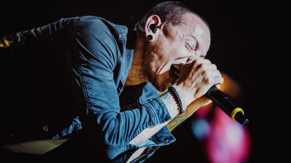 Chester Bennington of Linkin Park performing live on stage with microphone, delivering an intense rock performance under dramatic lighting