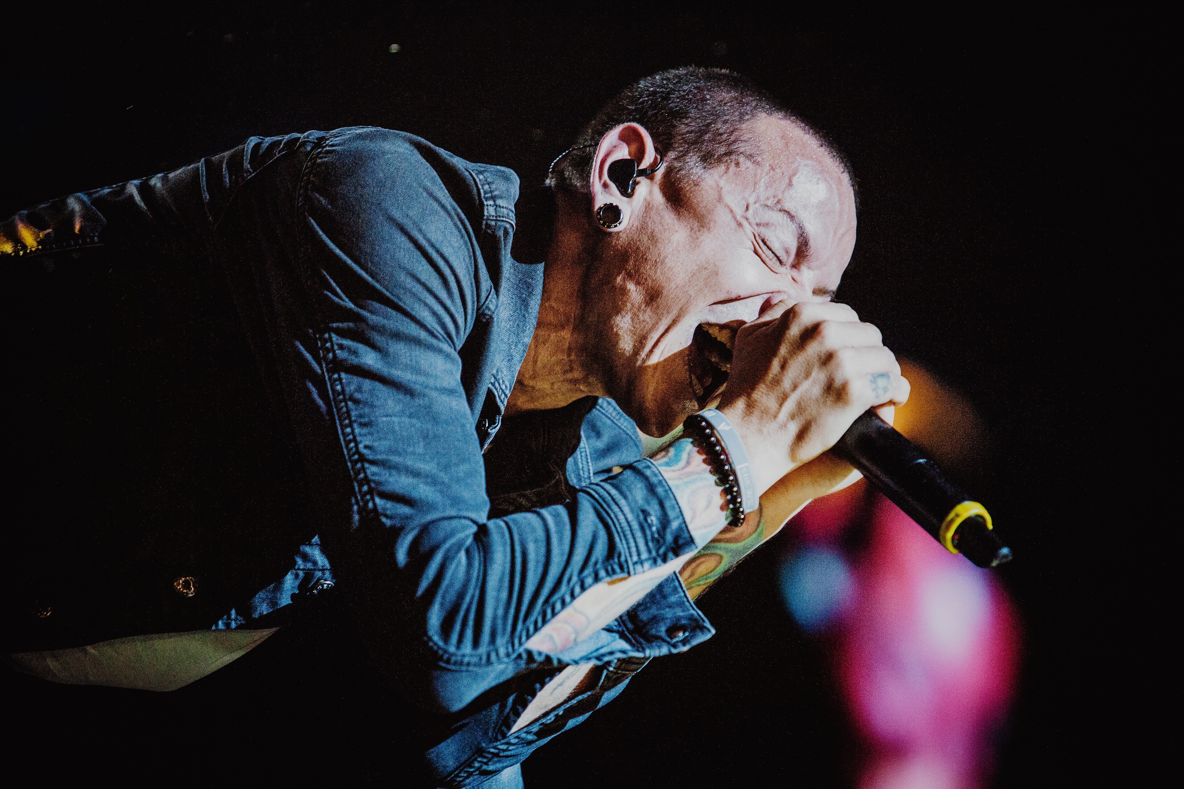 Chester Bennington of Linkin Park performing live on stage with microphone, delivering an intense rock performance under dramatic lighting