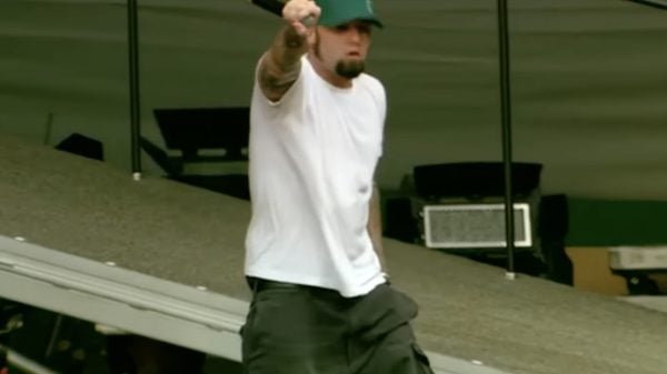 Fred Durst, frontman of Limp Bizkit, performing live on stage in 2003 with microphone, energetic stance, and dramatic stage lighting.