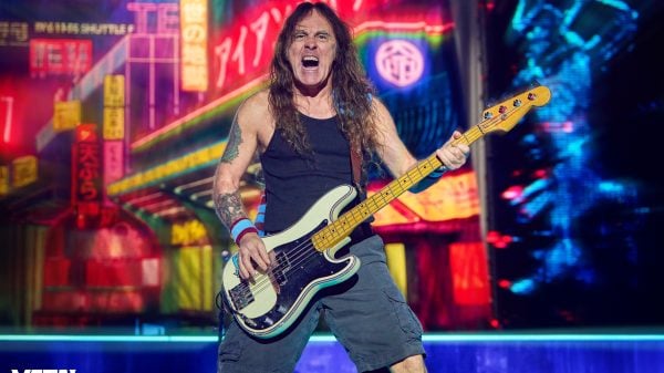 Steve Harris, bassist of Iron Maiden, performing live on stage with his signature bass guitar under dramatic concert lighting