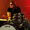 Joey Cassata sitting behind his drum kit in a promotional photo.
