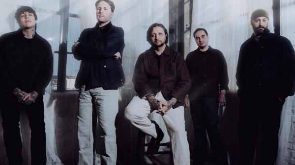 Members of Erra posing together in a professional promotional band photo, wearing modern metal attire with a serious expression.