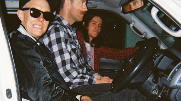 Three members of Stepmother seated together during a video shoot, led by underground guitarist Graham Clise, in a professionally filmed setting. ????️ Title Stepmother Featuring Graham Clise – Seated Video Shoot Portrait ???? Description Three members of Stepmother seated together during a video shoot, led by underground guitarist Graham Clise, in a professionally filmed setting.